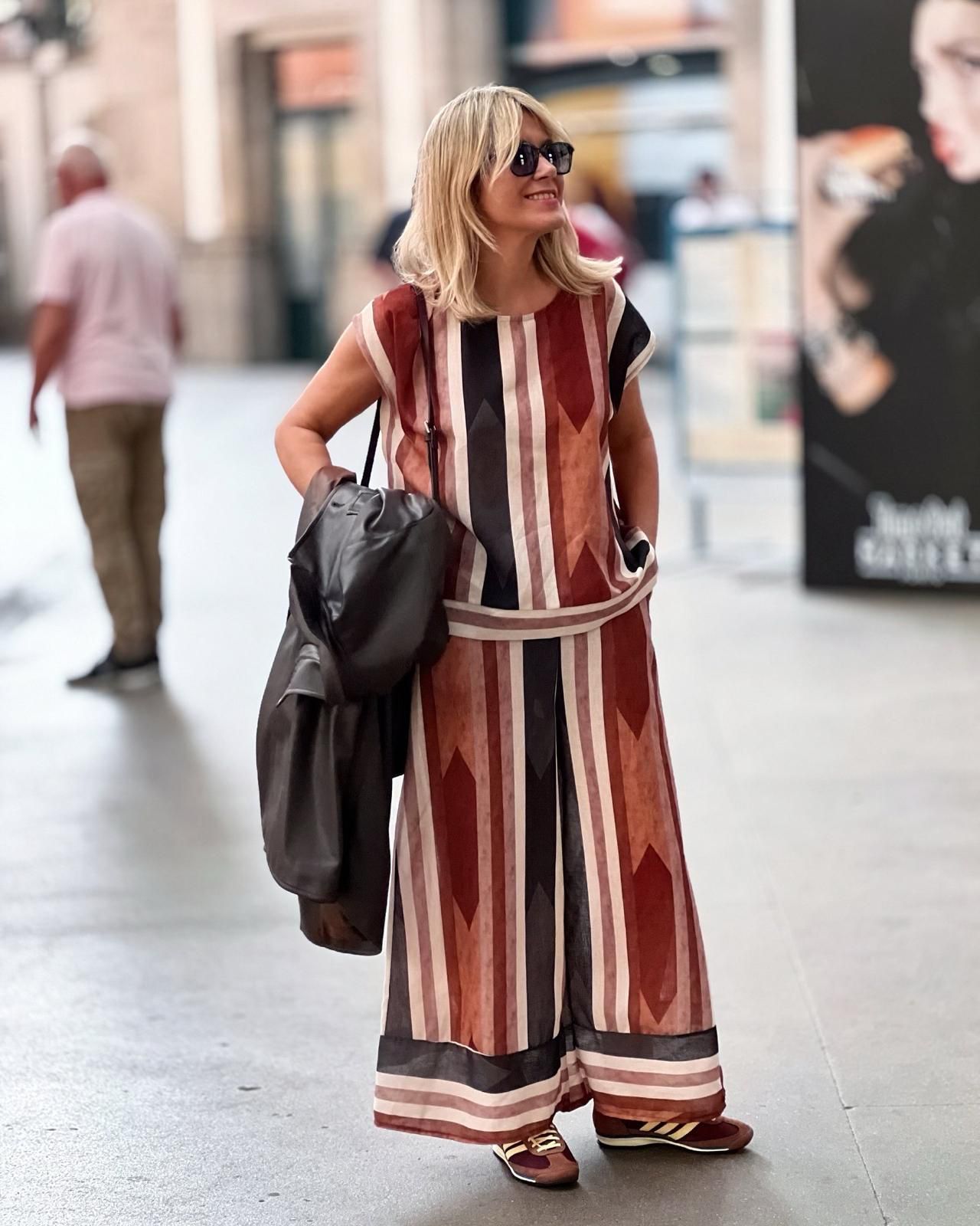 Mulher com roupa de padrão geométrico vermelho e castanho numa rua urbana