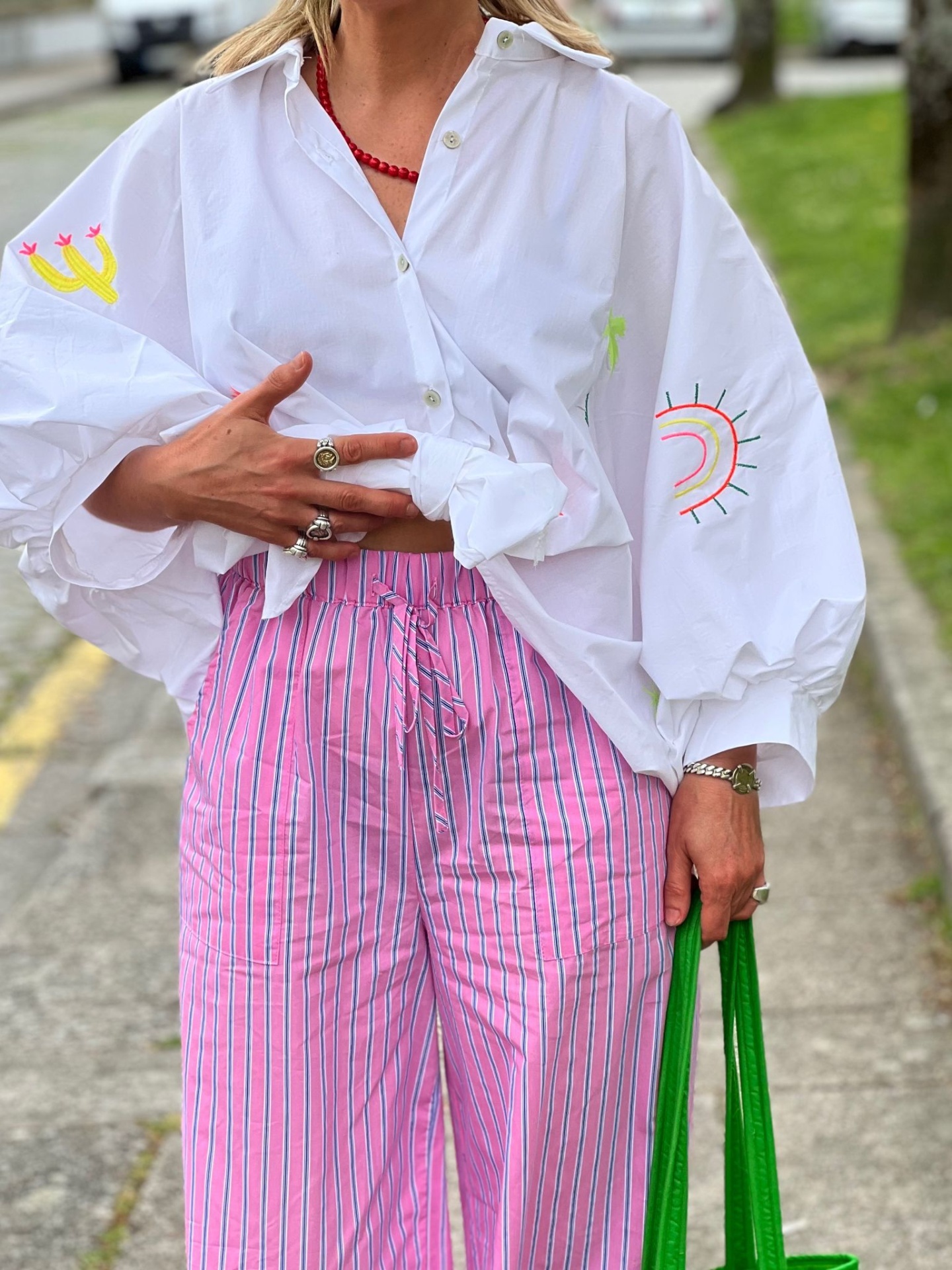 Roupa casual com camisa branca bordada e calças riscas rosa na rua