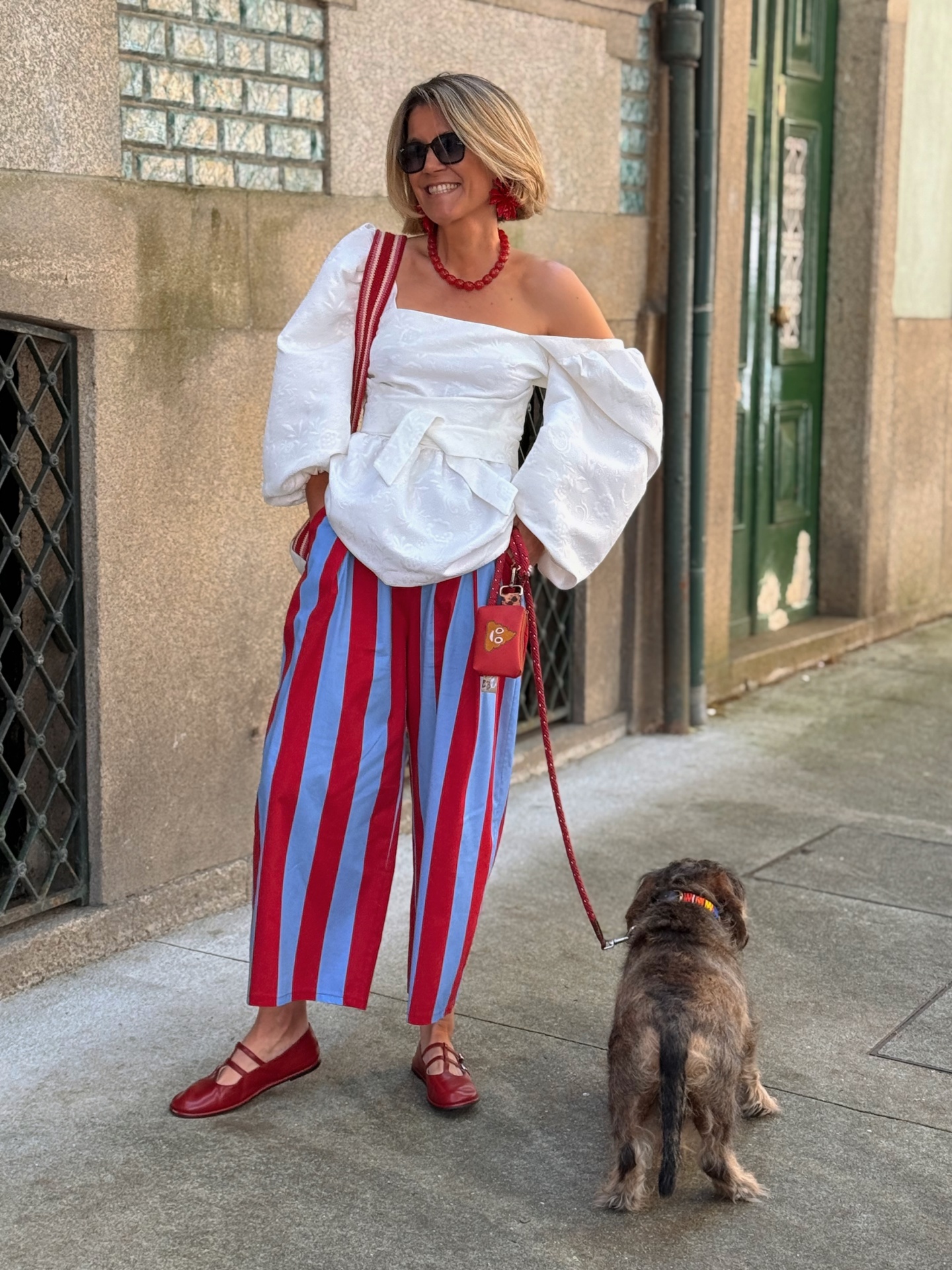 Mulher com roupa colorida e cão na trela numa rua