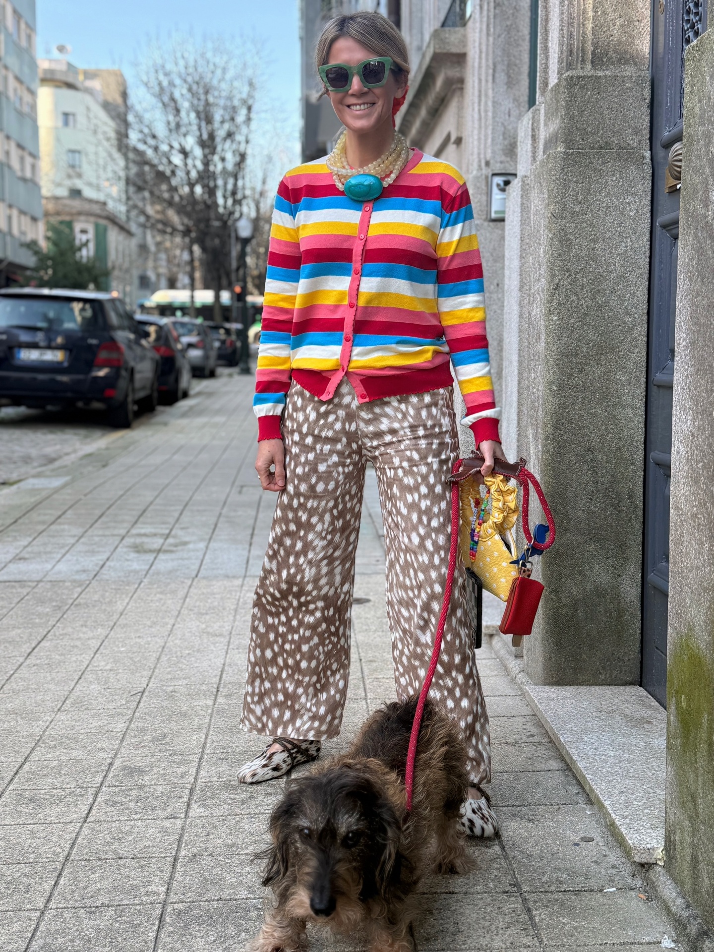 Mulher de suéter riscado colorido e calças estampadas com cão numa rua urbana