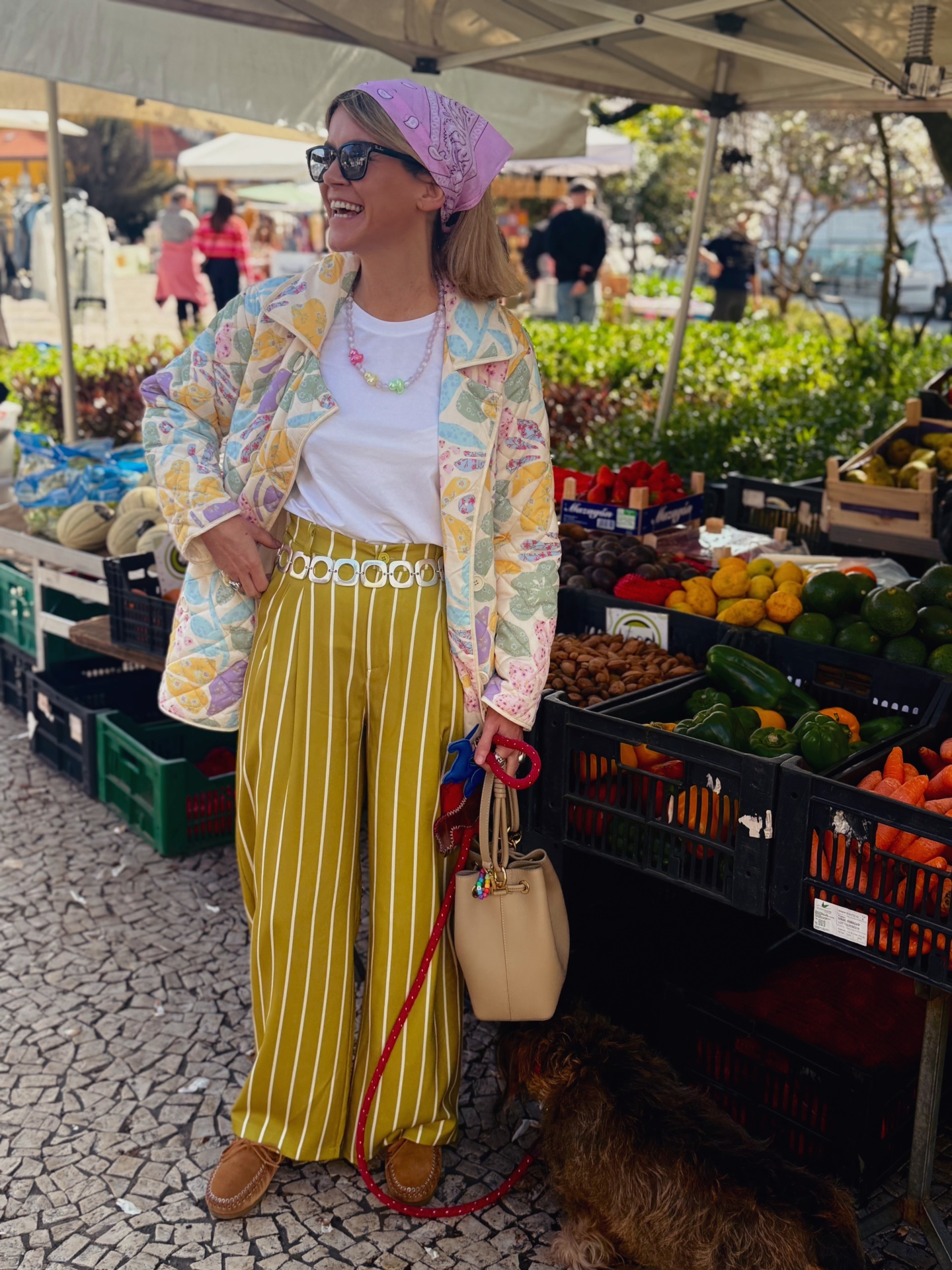 Mulher em mercado ao ar livre com roupa colorida e cão