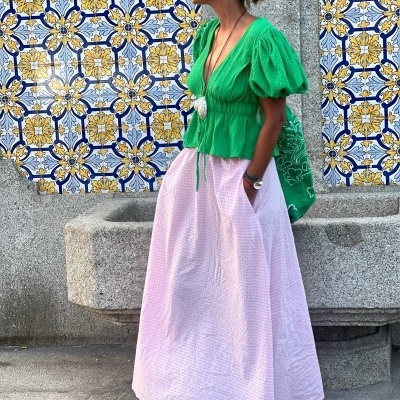 Mulher de roupa verde e rosa ao lado de azulejos azuis e amarelos com texto Fonte de Villar