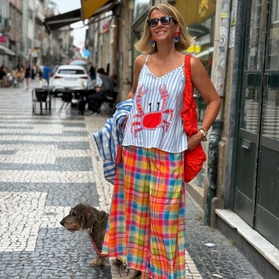 Mulher com vestido e blusa colorida numa rua com calçada portuguesa