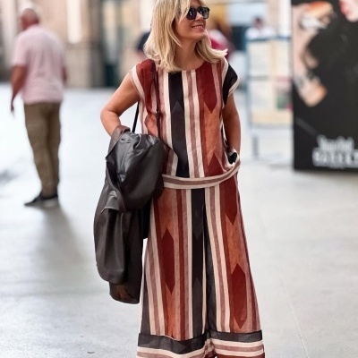 Mulher com roupa de padrão geométrico vermelho e castanho numa rua urbana