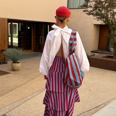 Mulher com chapéu vermelho e roupa com riscas vermelhas e azuis