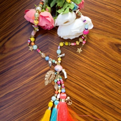 Colar colorido com pendentes e flores artificiais sobre madeira