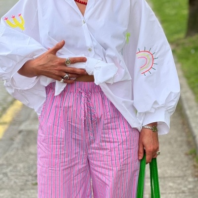 Roupa casual com camisa branca bordada e calças riscas rosa na rua