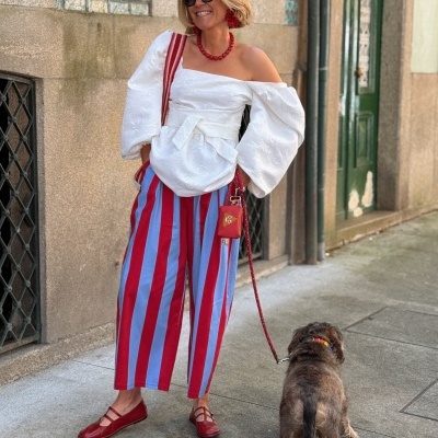 Mulher com roupa colorida e cão na trela numa rua