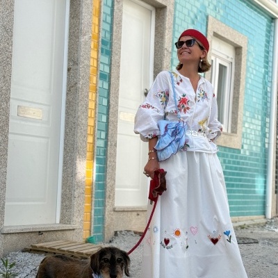 Mulher com vestido branco bordado e cão em rua com azulejos coloridos