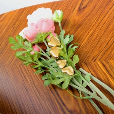 Ramo de flores artificiais com sinos dourados sobre mesa de madeira