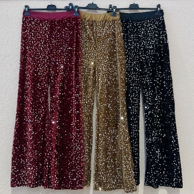 Três calças com lantejoulas em vermelho, dourado e preto penduradas