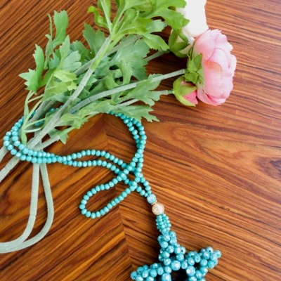 Colar azul claro em forma de estrela e flores sobre mesa de madeira