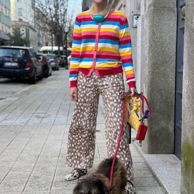 Mulher de suéter riscado colorido e calças estampadas com cão numa rua urbana