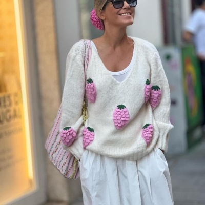 Camisola branca com morangos 3D rosa e verde, mulher com saia branca e óculos escuros numa rua