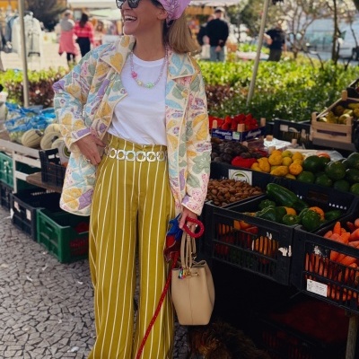Mulher em mercado ao ar livre com roupa colorida e cão