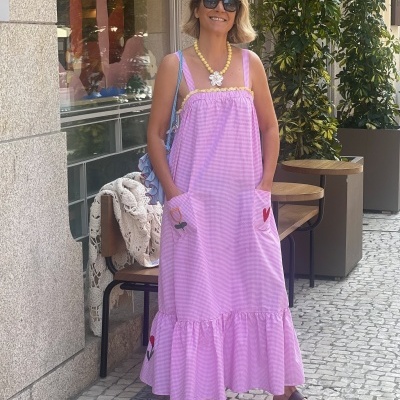 Vestido rosa comprido com padrão xadrez miúdo branco e detalhes amarelos, usado com colar amarelo e sandálias castanhas