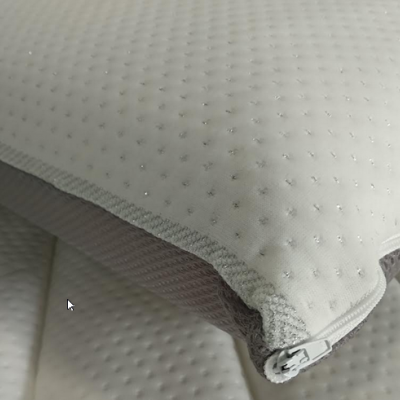 Travesseiro branco com pontos em relevo, borda cinza com zíper