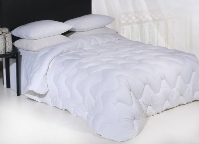 Edredão branco acolchoado em cama com almofadas brancas