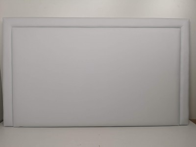 Cabeceira estofada branca rectangular em tecido colocado contra parede branca