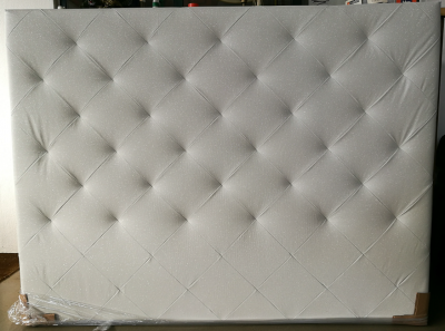 Cabeceira de cama estofada branca com padrão capitonê.