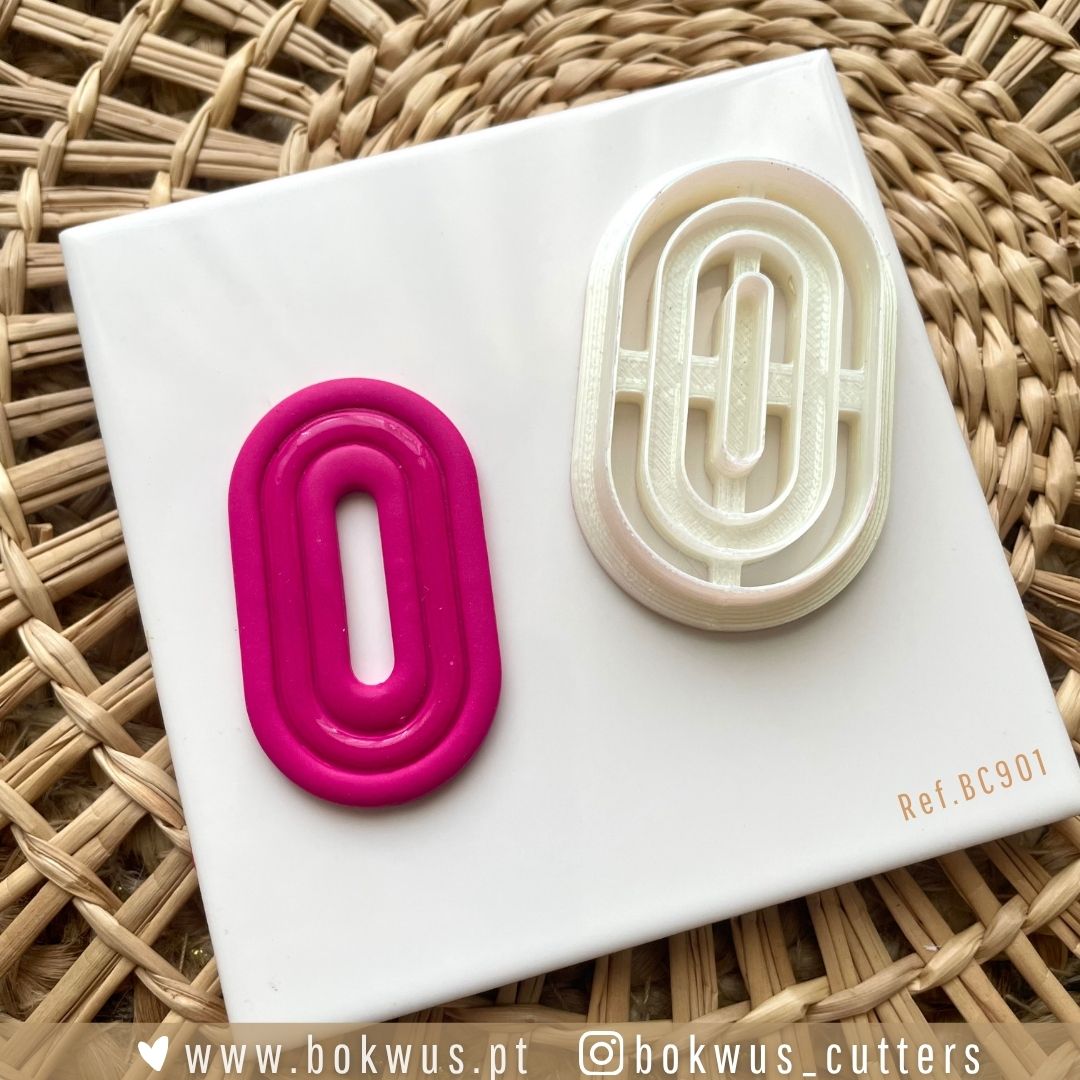 Cortador Geométrico (5cm) - Versão Sólida e Vazada Dois cortadores de biscoitos ovais rosa e branco sobre base branca em superfície trançada.