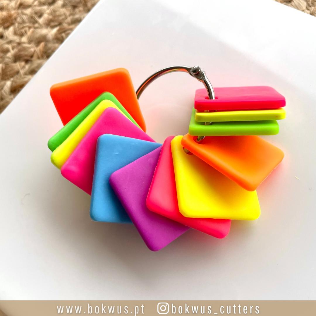 Anel metálico com quadrados plásticos coloridos sobre superfície branca