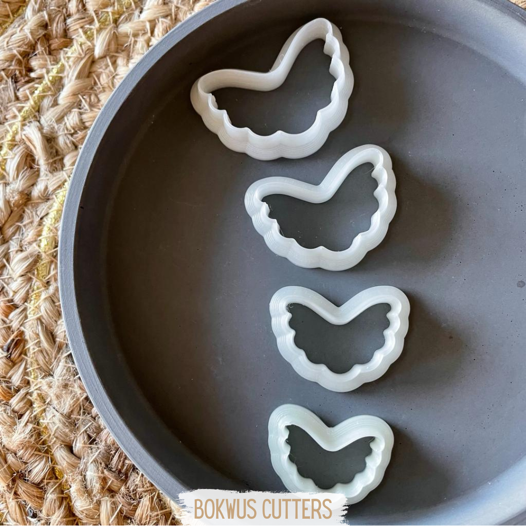 Conjunto de 4 cortadores - BC006 Quatro cortadores brancos em forma de coração dentro de prato cinza sobre superfície trançada