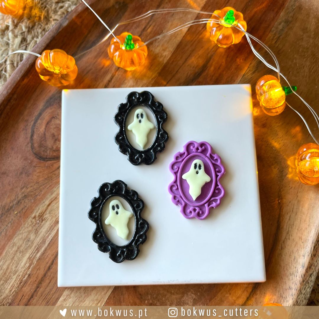 Moldura & Fantasma - Disponível em conjunto ou individualmente Três moldes de silicone com fantasmas em molduras preta e roxa sobre placa branca com luzes de abóboras