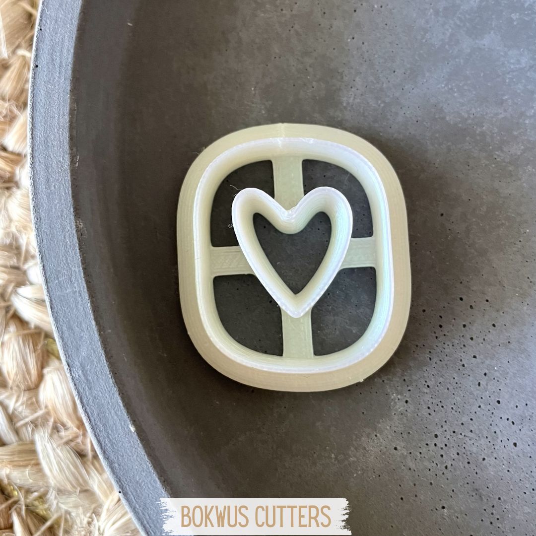 Cortador | BC115 Cortador de biscoitos branco em forma de coração dentro de retângulo, numa tigela cinzenta.