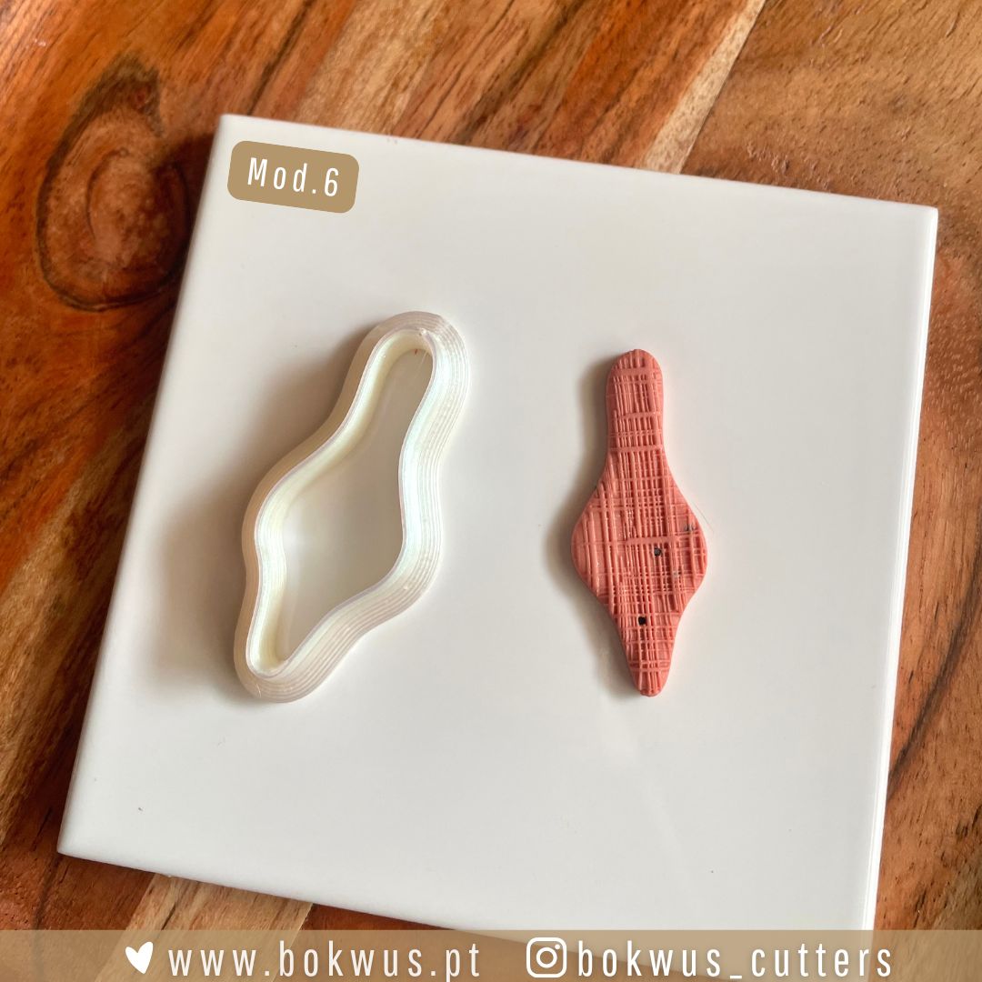 Cortadores formas orgânicas Molde de corte e peça de massa modelar rosa texturizada sobre superfície branca e fundo de madeira