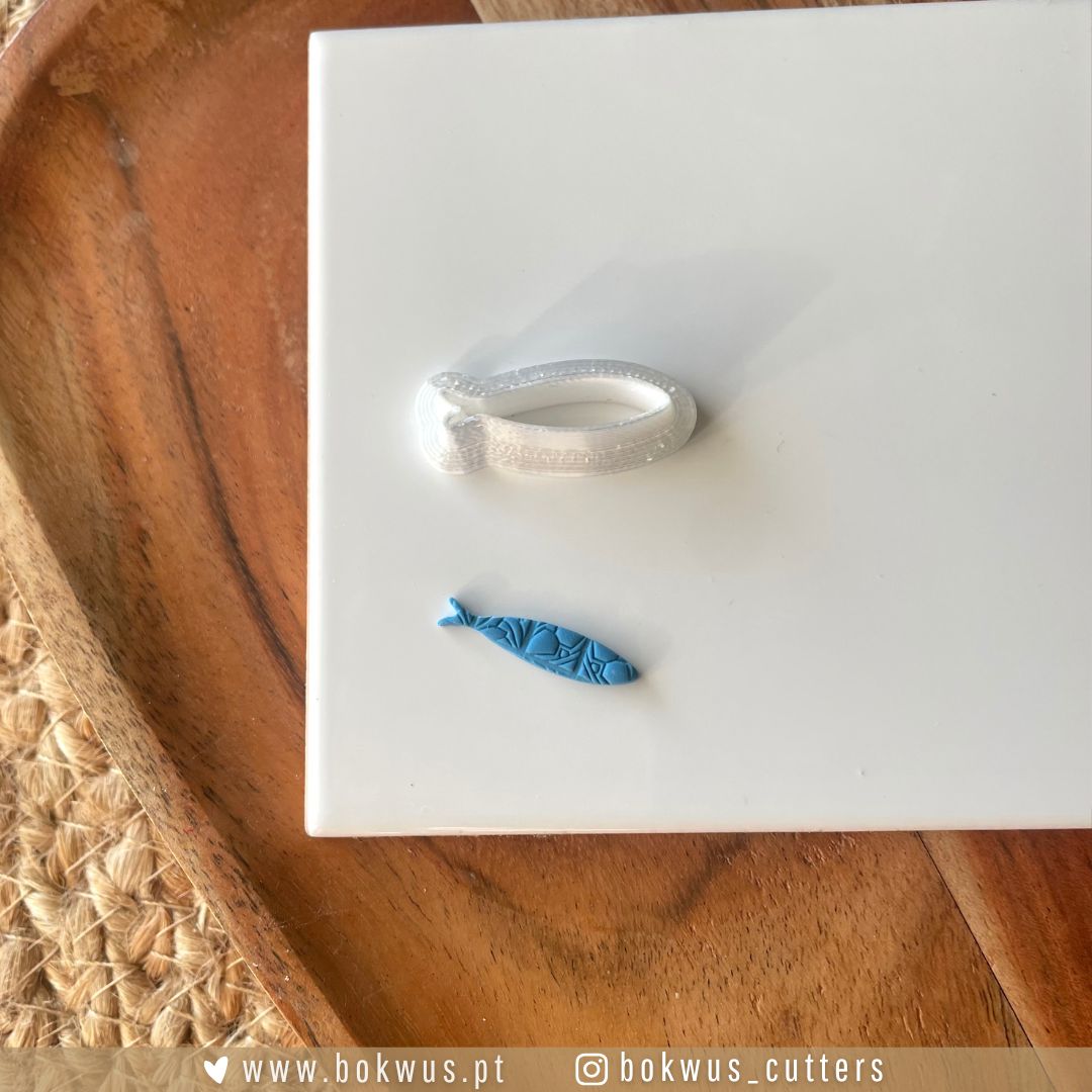 Cortador Sardinha | Disponível em 4 tamanhos Cortador azul em forma de peixe e laço branco sobre superfície branca e base de madeira