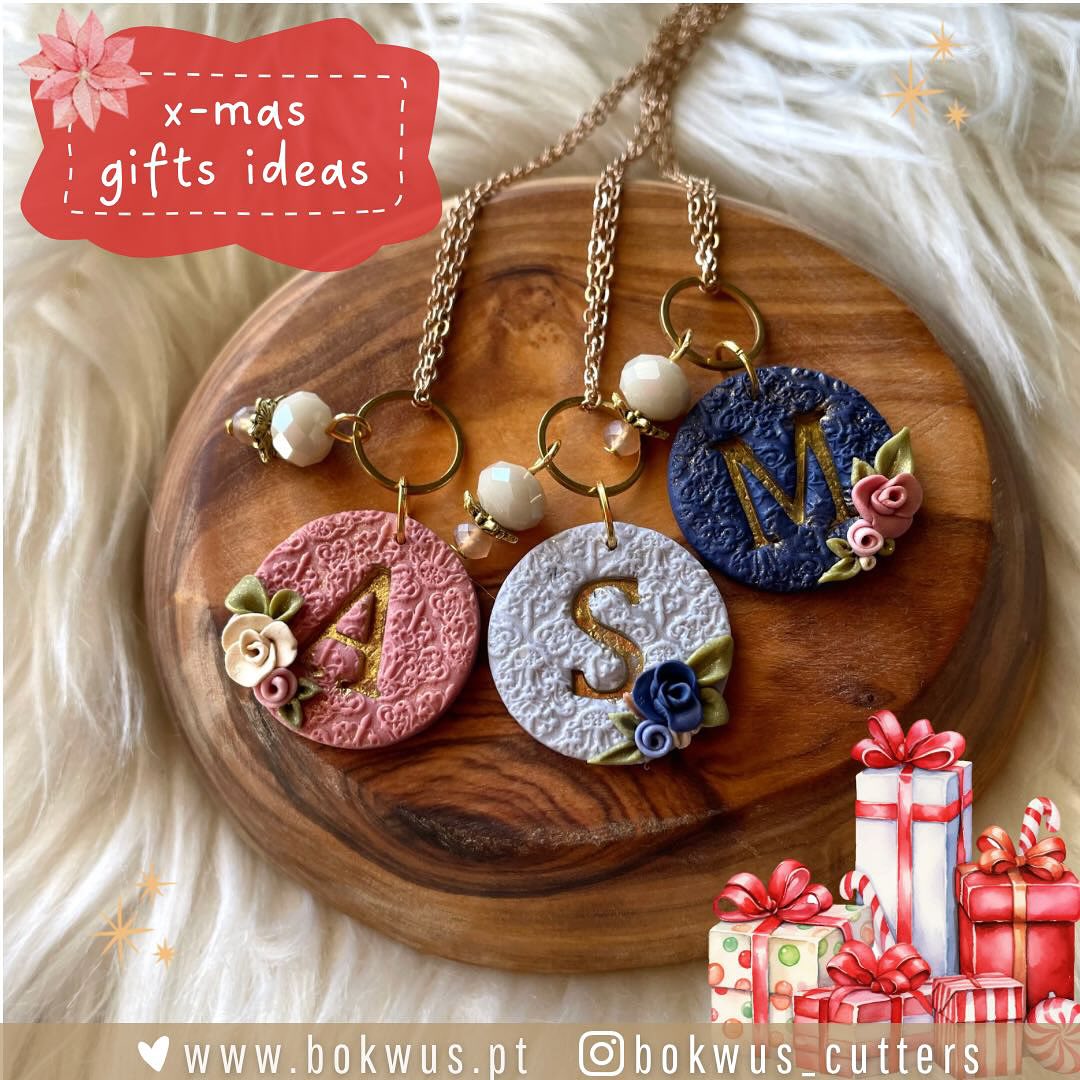 Três porta-chaves redondos coloridos com letras e flores em base de madeira