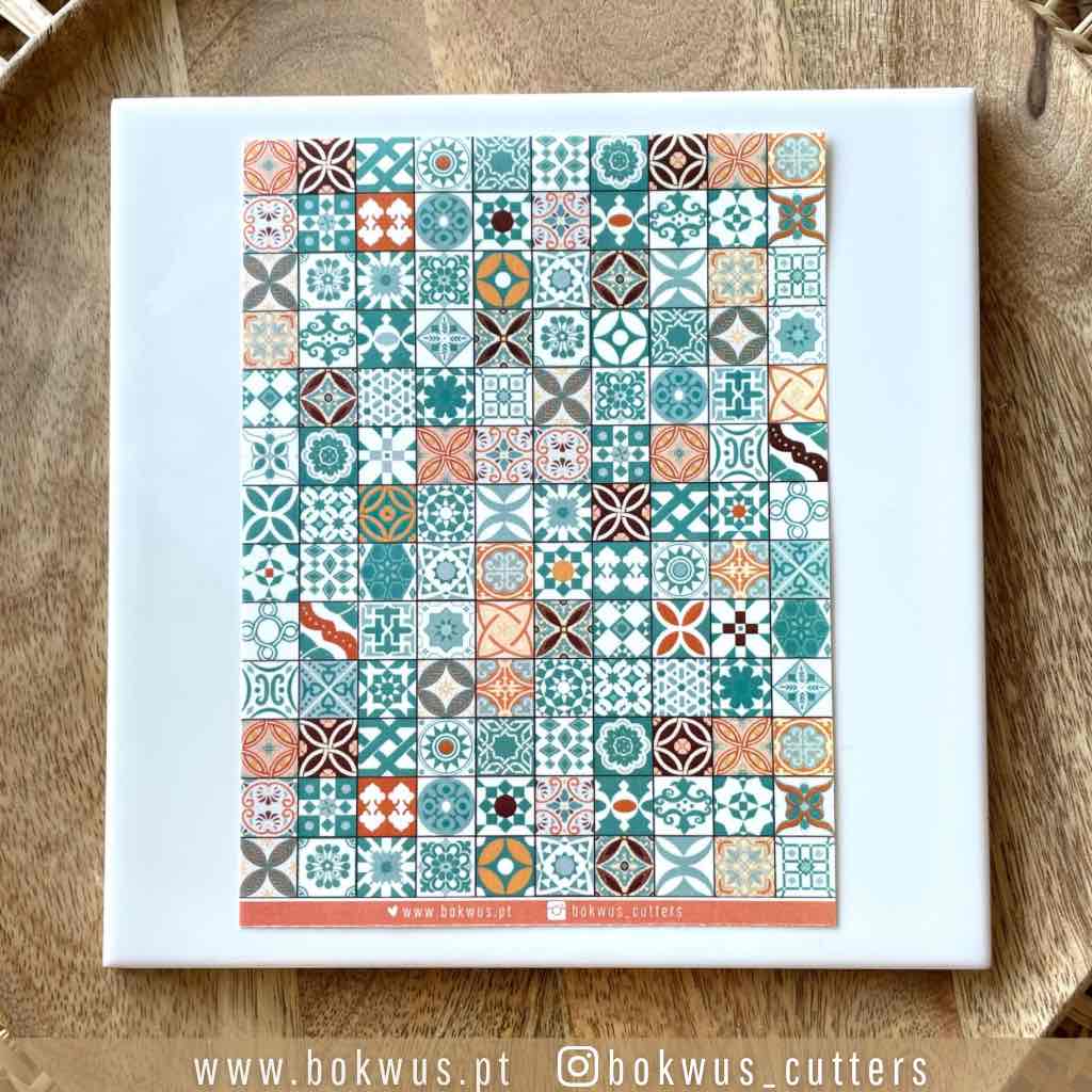 Papel tranfer - azulejo terracota Azulejo quadrado com padrão geométrico colorido sobre superfície de madeira clara.
