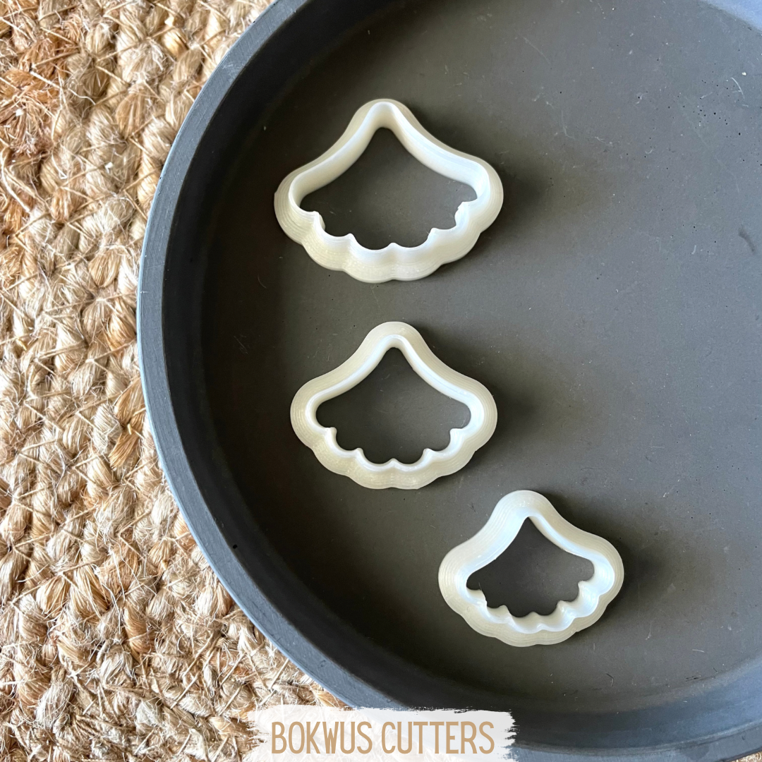 Conjunto de 3 cortadores - BC044 Três cortadores de massa brancos em prato preto sobre esteira de fibras naturais