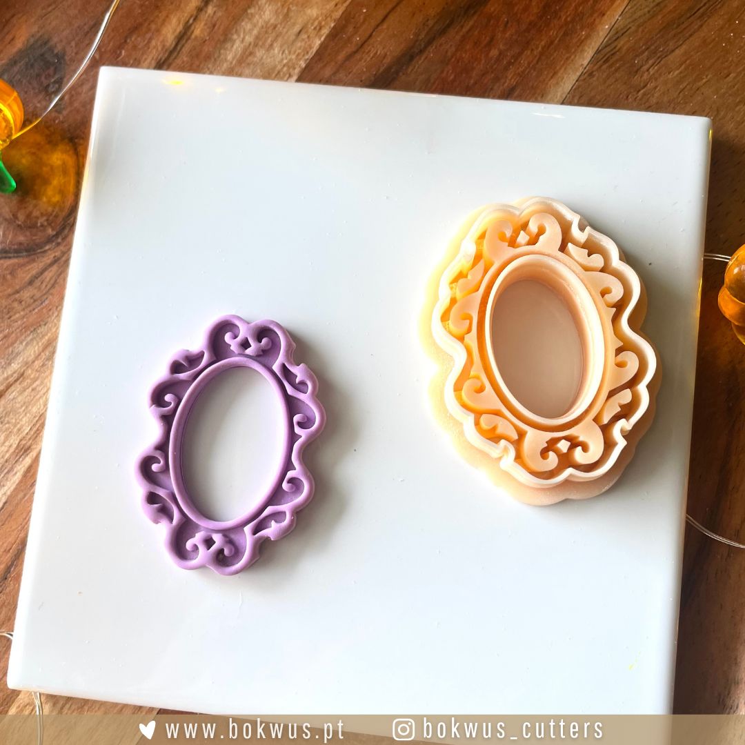Moldura & Fantasma - Disponível em conjunto ou individualmente Dois cortadores de biscoitos ovalados, um roxo e outro creme com detalhes laranja, sobre superfície branca