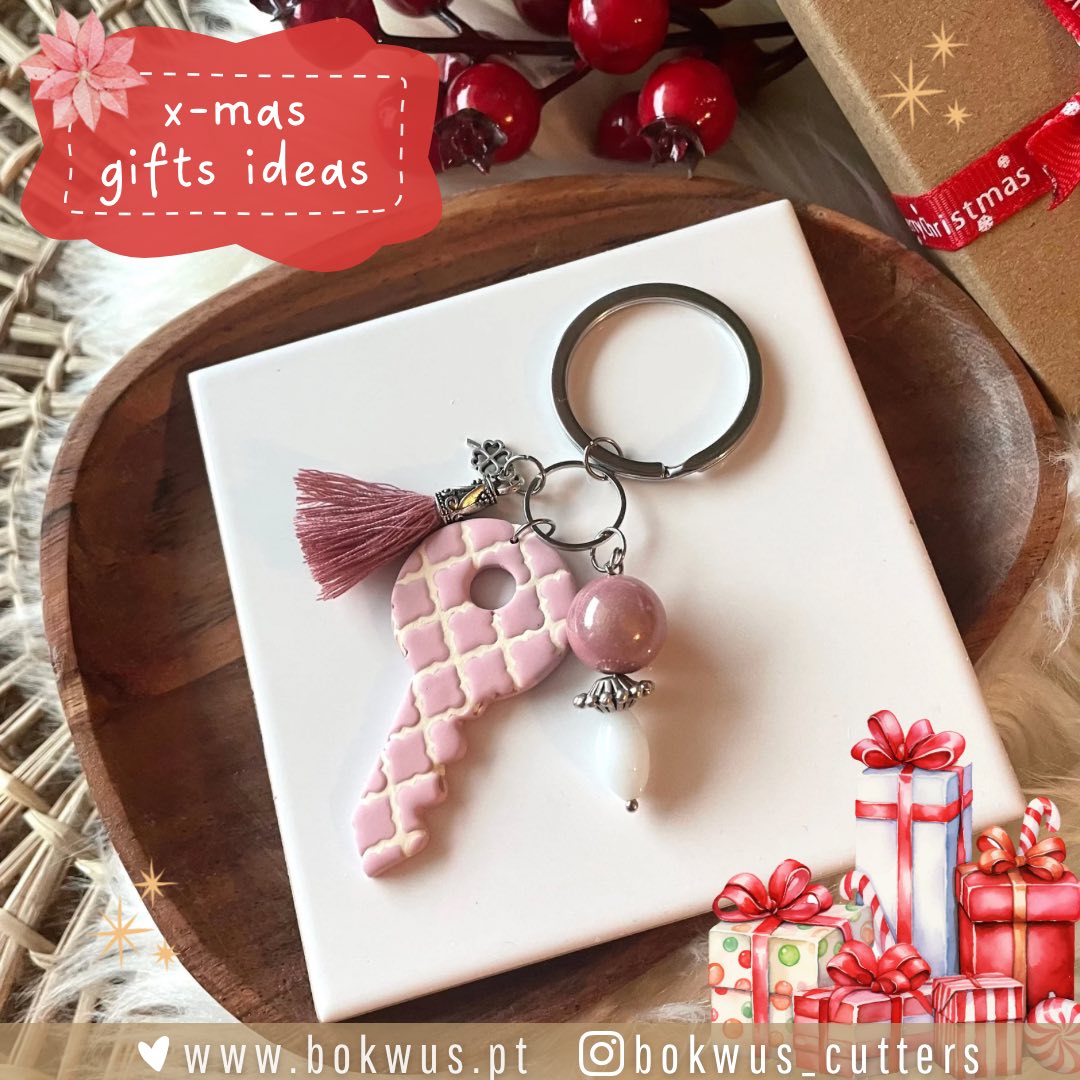 Chaveiro com chave rosa, bolas decorativas e tassel, sobre base branca num prato de madeira