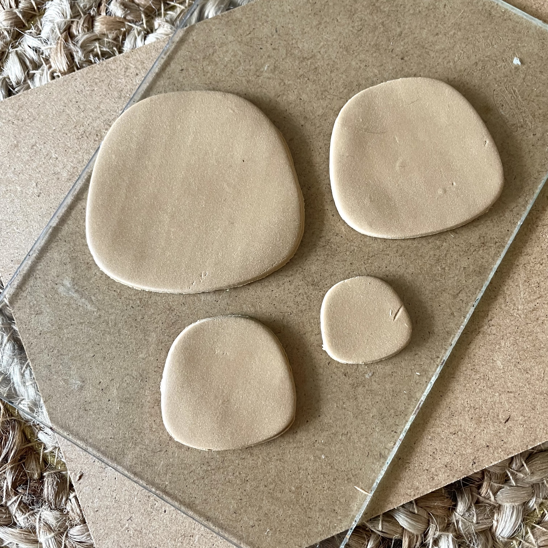 Conjunto de 4 cortadores - BC303 Peças de cerâmica bege claro em formas irregulares sobre vidro e madeira