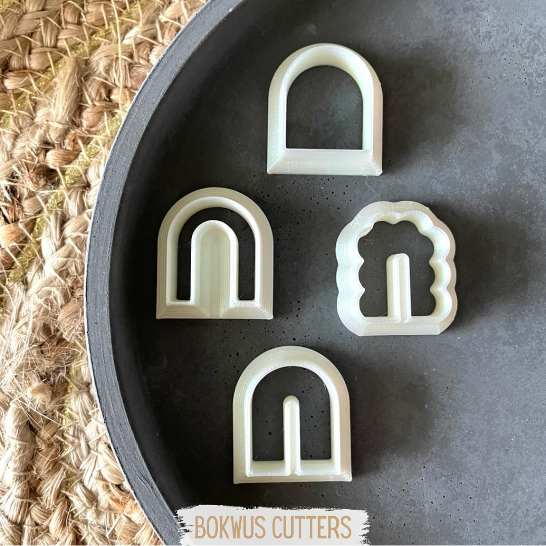 Conjunto de 4 cortadores - BC037 Conjunto de cortadores de massa brancos com formas variadas sobre prato cinza e base de fibra natural