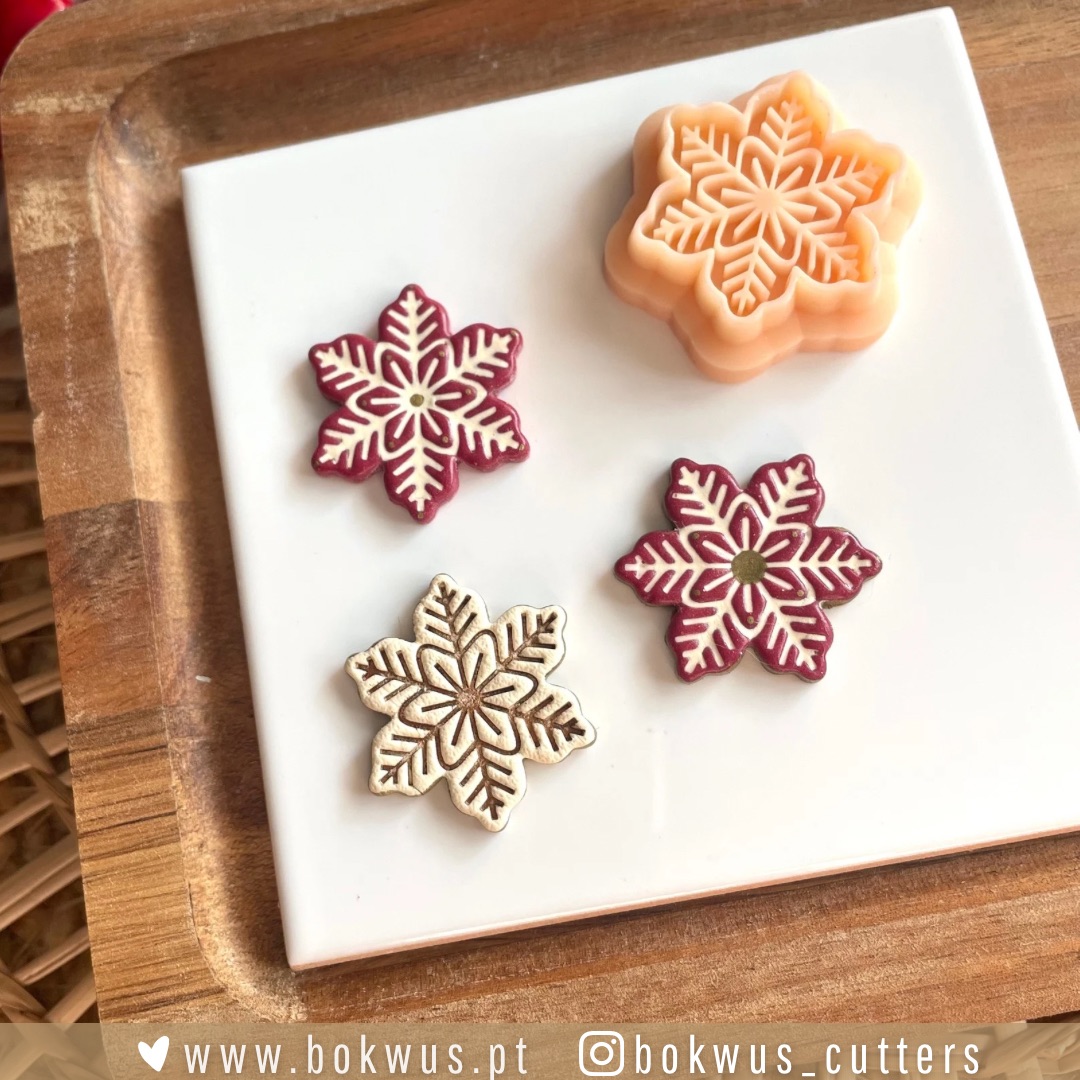 Hygge Noël | Coleção de Natal Moldes em forma de floco de neve em vermelho, creme e laranja num prato branco com base de madeira.