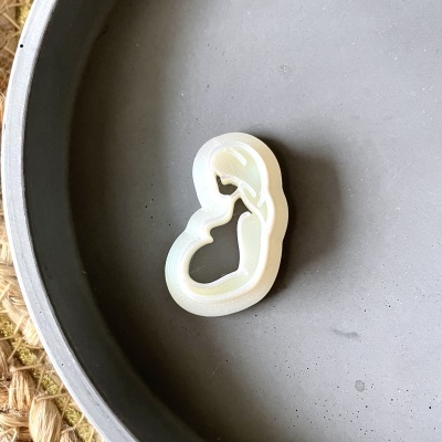 Formador de bolachas em formato de mulher grávida branco sobre prato cinza