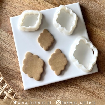 Cortadores de biscoitos brancos em formato de etiqueta e biscoitos moldados sobre base branca