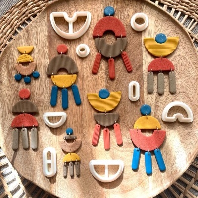 Brincos geométricos coloridos em prato de madeira