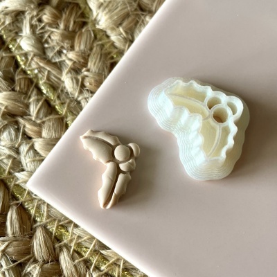 Dois moldes pequenos para decoração num mostrador rosa ao lado de tecido trançado natural