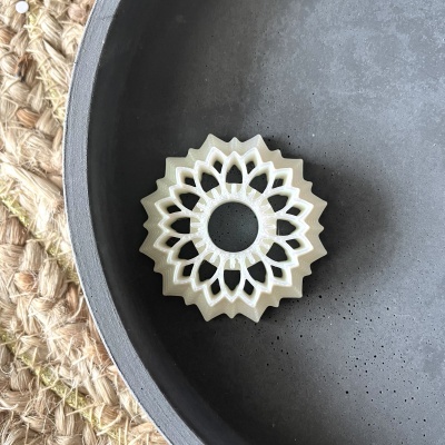 Marcador de livro branco em formato mandala dentro de prato cinza