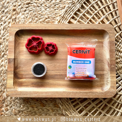 Embalagem Cernit Number One salmão, formas vermelhas de flor e recipiente de contas pretas num tabuleiro de madeira