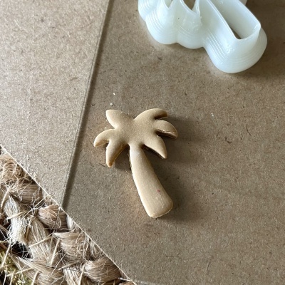 Objeto em forma de palmeira em madeira clara sobre superfície castanha claro