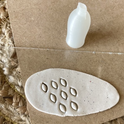 Base oval de cerâmica branca com relevos e vela branca pequena