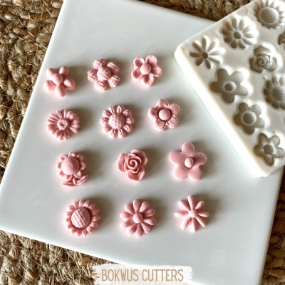 Flores rosa em prato branco ao lado de molde branco com relevos florais sobre superfície de palha