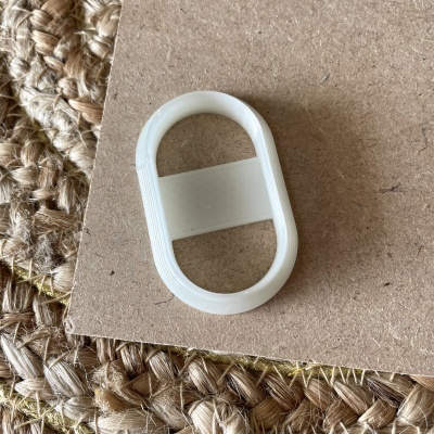 Forma oval branca em plástico sobre superfície castanha com tapete de fibra natural ao fundo