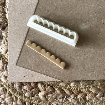 Peças plásticas branca e bege com formato de bagas sobre superfícies marrons e tecido de juta